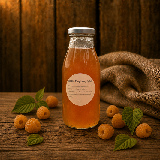 Bottle of golden raspberry syrup with raspberries and leaves on a wooden surface